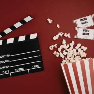 a clapperboard, popcorn box and popcorn, and two ticket stubs that say 